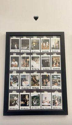 a black frame with pictures on it and a heart hanging from the wall behind it