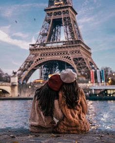 two people sitting on the ground in front of the eiffel tower