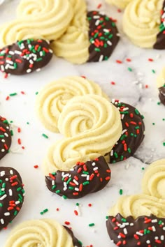 chocolate covered cookies with sprinkles and white frosting on a marble surface