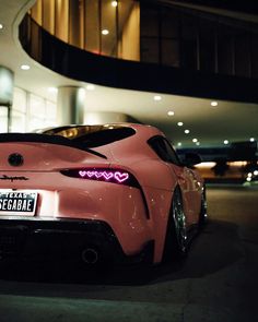 a pink sports car parked in front of a building