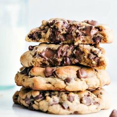 chocolate chip cookies stacked on top of each other with a glass of milk in the background