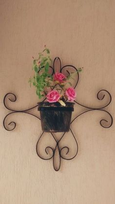 a potted plant is hanging on a wall with wrought iron designs and pink flowers