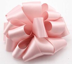 a large pink bow on top of a white surface with clippings to the side