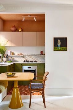 a small kitchen with green cabinets and white flooring is seen in this image from the dining room