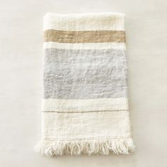 a white and grey towel with fringes on it sitting on top of a table