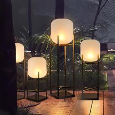 three lamps sitting next to each other on top of a wooden floor in front of trees