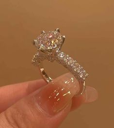 a person holding a ring in their left hand with a diamond on the top and side