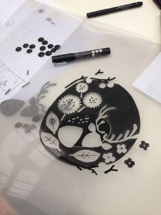 a black and white paper cut out of a skull on a table next to some crayons