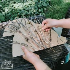 someone is making sticks out of twigs on top of a wicker table in the garden