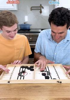 two young men playing an interactive game on a kitchen counter top with the words jalobjob in front of them