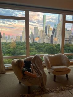 a person sitting in a chair with a laptop on their lap looking out the window