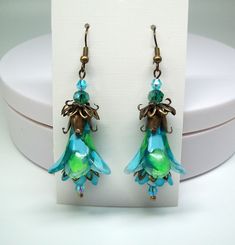 Green flower earrings, Boho earrings, Dangle & drop earrings. Hand painted and color sealed (permanent). Wonderful lime green, baby blue and turquoise trumpet flowers accompanied by turquoise mini-inner flowers with turquoise and green faceted crystal accent beads. Dressed up or down no matter the occasion these colorful floral statement earrings are sure to compliment you.  Earrings are lightweight and can be worn comfortably all day long. Gift for mom? Friendship gift for her? Coworker gift? B Whimsical Blue Drop Earrings, Whimsical Blue Jewelry With Flower Charm, Blue Whimsical Dangle Flower Earrings, Whimsical Blue Dangle Flower Earrings, Artistic Green Flower-shaped Jewelry, Turquoise Dangle Earrings With Flower Charm, Handmade Turquoise Flower-shaped Earrings, Whimsical Green Dangle Jewelry, Whimsical Green Jewelry