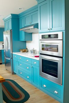 a kitchen with blue cabinets and stainless steel appliances, including an oven that is built into the wall