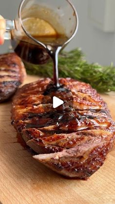 someone is pouring sauce on top of some meat that is sitting on a cutting board