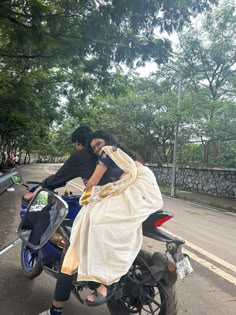 a man and woman riding on the back of a motorcycle