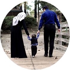 a man holding the hand of a little boy as he walks down a wooden bridge