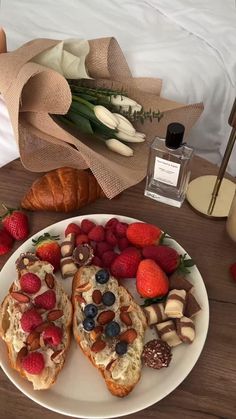 two pieces of bread on a plate with strawberries, raspberries and almonds