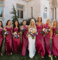 a group of women standing next to each other in front of a building with flowers