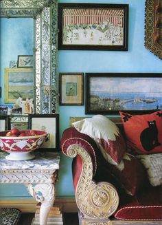 a living room with blue walls and pictures on the wall, including a red couch