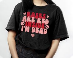 a woman wearing a black t - shirt that says roses are red inside i'm dead