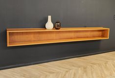 two vases are sitting on a shelf in the corner of a room with parquet flooring