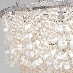 a chandelier with white shells hanging from it's side and the light is on