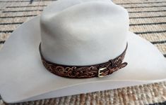 "Hat Band hand tooled, hand carved and hand sewn leather . It is made from 3 - 4 oz. vegetable tanned leather*. It is dyed, covered with a special compound** to protect against moisture, and finished with a clear gloss giving it a lasting shine. Items upon an order are ready for shipment in 4-6 weeks. I can offer a lot of patterns! There are 5 - 7 holes in the Hat Band. Width of the hatband: 1 1/4\" - 1 1/2\" ranger type. I can customise size, width, tint etc. If you need a different size than a Custom Handmade Leather Hat Bands, Custom Leather Hat Bands For Western-themed Events, Artisan Leather Hat Bands For Western-themed Events, Handmade Western Leather Hat, Hand Sewn Leather, Vegetable Leather, Clear Gloss, Leather Hats, Tooled Leather