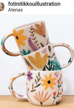 three coffee mugs are stacked on top of each other, one is decorated with flowers