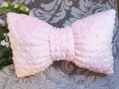 a pink bow tie laying on top of a pillow next to a bouquet of flowers