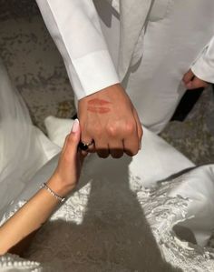 a man and woman holding hands while sitting on the ground in front of each other