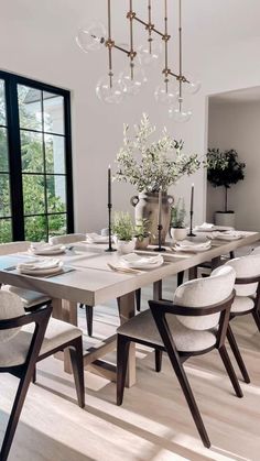 a dining room table with white chairs and a vase filled with flowers on top of it