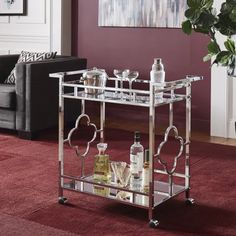 a silver bar cart with drinks on it in front of a red carpeted living room