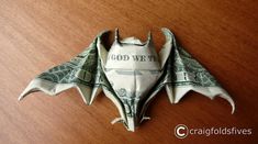 a dollar bill origami bat sitting on top of a wooden table