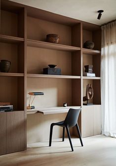 a chair sitting on top of a wooden floor next to a book shelf filled with books