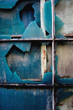 peeling paint on the side of a building with broken glass and chipped up windows