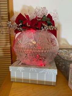 a pink vase with red flowers on top of a box next to a christmas ornament