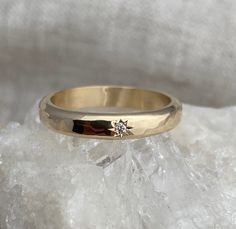 a yellow gold ring with a diamond on top of some ice crystals and white rock