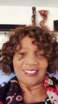 a woman with curly hair smiling at the camera