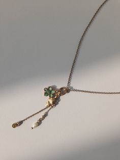 Adorn yourself with the whimsical charm of nature with this delightful necklace featuring four dangling treasures. A petite green flower, a delicate leaf, a shimmering stone, and a lustrous pearly accent sway gracefully from the dainty chain, creating a captivating ensemble that captures the essence of natural beauty. Whether worn alone or layered with other favourites, this enchanting piece adds a touch of elegance and allure to any look. Green Dangle Charm Necklace, Green Dangle Charm Necklaces, Green Charm Necklace With Dangling Charms For Gift, Green Jewelry With Dangling Charms As Gift, Green Jewelry With Dangling Charms For Gift, Elegant Metal Necklaces With Dangling Charms, Green Necklaces With Dangling Charms As Gift, Green Necklaces With Dangling Charms For Gifts, Green Necklace With Dangling Charms As Gift