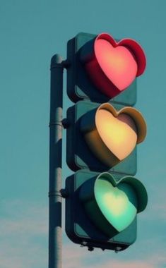 a traffic light with two hearts on it's red and green lights in front of a blue sky