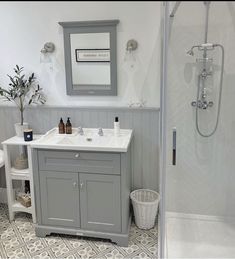 a bathroom with gray cabinets and white fixtures