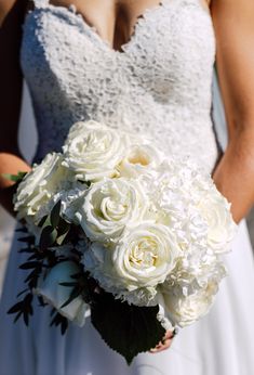 a bride holding a bouquet of white roses