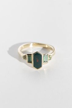 Art deco inspired ring with bloodstone and green tourmaline. Bloodstone is inlaid into the elongated hexagon, measuring 9.5mm x 5mm. Accent tourmalines are approximately .30 total carat worth. Millimeter measurement from end to end is 15mm. 14k yellow gold setting, and the band is 1.75mm thick. Please leave a note at c Horizontal Gemstone Ring, Art Deco Ring Emerald, Artist Engagement Rings, Bloodstone Ring Engagement, Emerald Green Engagement Rings, 5 Stone Engagement Rings, Bloodstone Engagement Ring, Green Garnet Ring, Baguette Band Engagement Ring