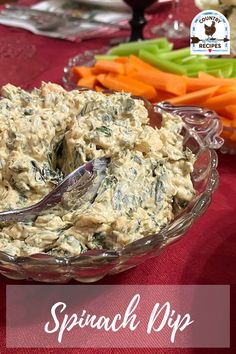 spinach dip in a glass bowl with carrots and celery on the side