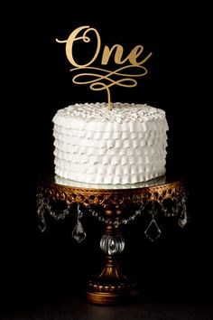 a white cake sitting on top of a gold plate with the word'finally'written on it