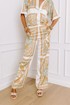 - Step into the spotlight with these fabulous satin-finished pants! Its charming relaxed fit is both trendy and classy, while the ornate print adds a dash of elegance and fun. Perfect for any occasion, this piece is your new go-to for effortlessly chic energy. - Fully lined material with an ornate print featuring mustard, blue, and neutral hues and satin finish - Side zip closure - Functional side pockets - A relaxed silhouette that ends in straight hemlines Measurements S : Front Rise 12.5", Hi Chic Patterned Printed Pants, Chic Printed Patterned Pants, Chic Beige Satin Bottoms, Beige Satin Bottoms For Spring, Chic Paisley Print Bottoms For Spring, Chic White Printed Bottoms, Elegant White Printed Bottoms, Elegant Printed Summer Pants, White Satin Bottoms For Summer