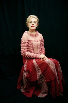 a woman sitting on top of a chair wearing a red dress