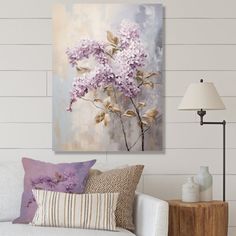 a living room with a white couch and purple flowers on the wall in front of it