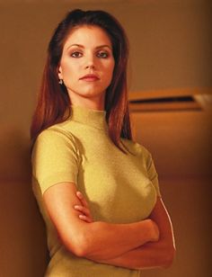 a woman with her arms crossed posing for a photo in a yellow top and skirt