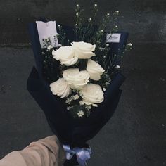 a bouquet of white roses is held by someone's hand